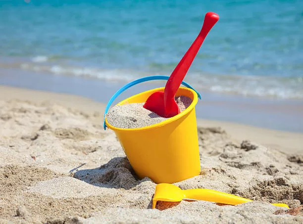 Yellow sand pail and shovel on a beach